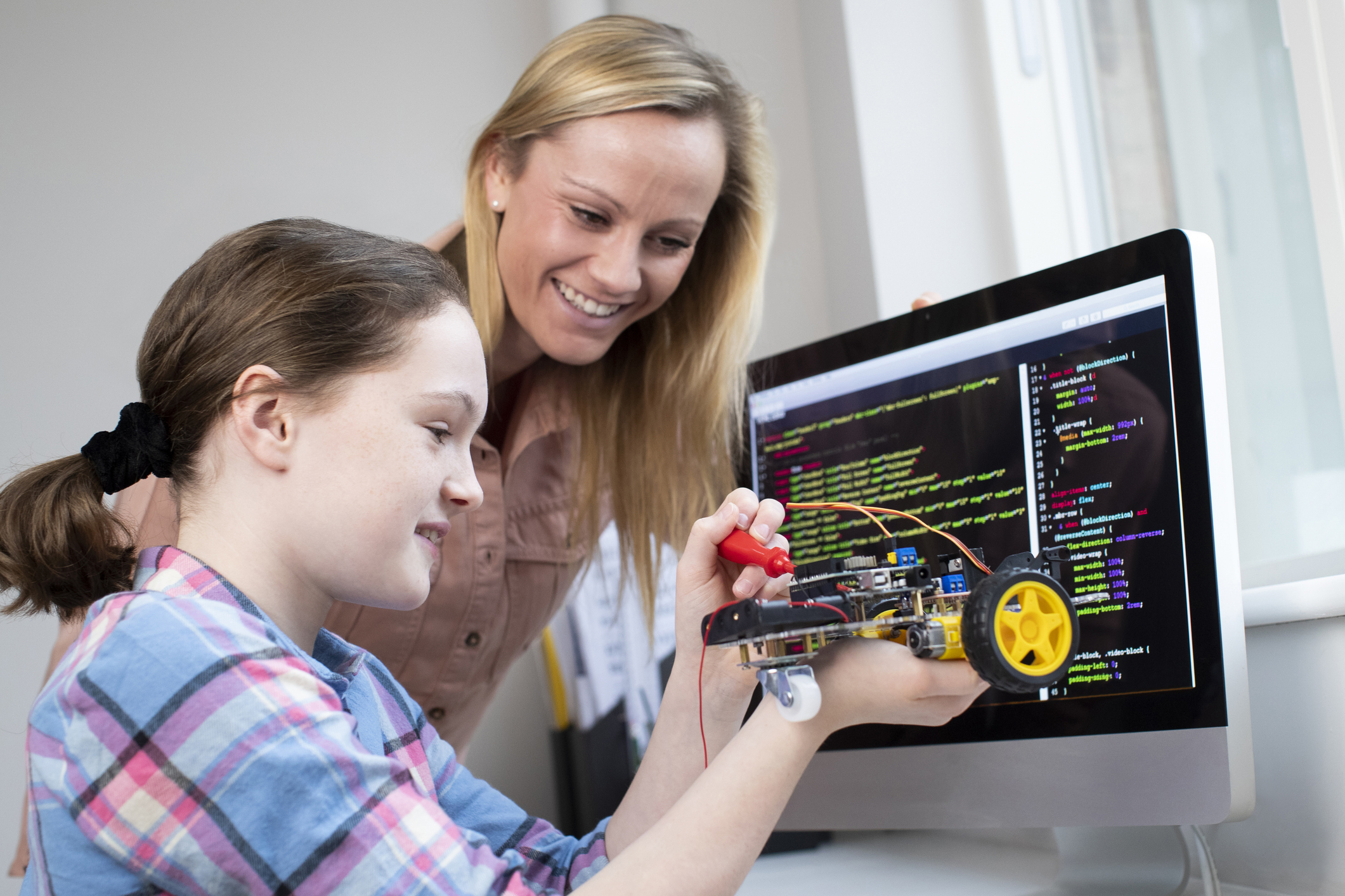 Teacher with middle school aged girl, building robot, mental health tips for caregivers and school staff