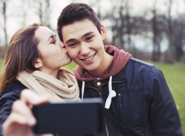 A girl kissing her boyfriend on the cheek