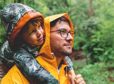 A father and son outside in the rain