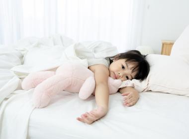 Sick toddler girl in bed with teddy bear