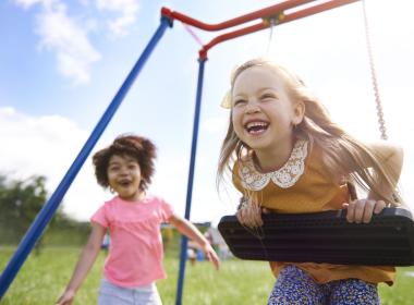 Two young girls playing joyfully on playground