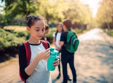 Preteen girl outside drinking water