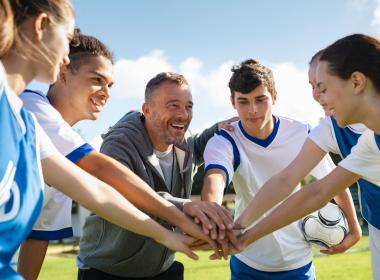 Group of teen soccer players with coach, cheering