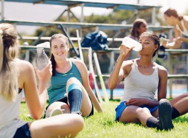 Group of teen female athletes drinking water on field