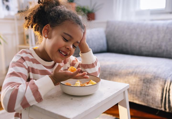 School age child eating a bowl of fruit