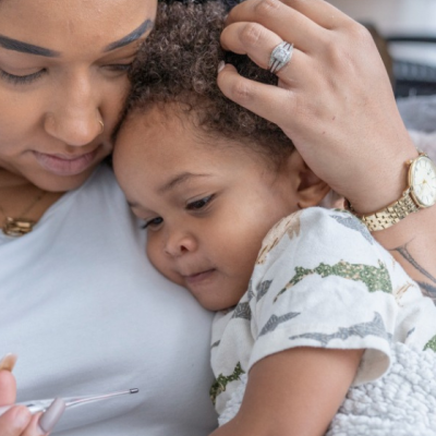 mom holding hugging baby taking her temperature