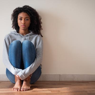 Young girl sits on floor, feeling sad and depressed.