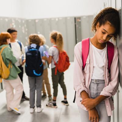 Preteen girl leaning against locker, not thrilled