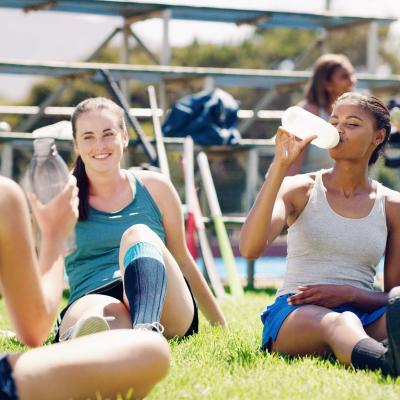 Group of teen female athletes drinking water on field