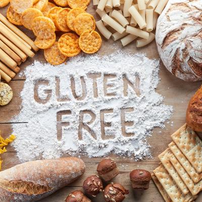 Rice, pastas and breads surrounding a pile of flour in which "gluten free" is written