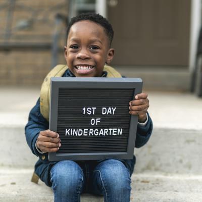 Child on his first day of school holding sign
